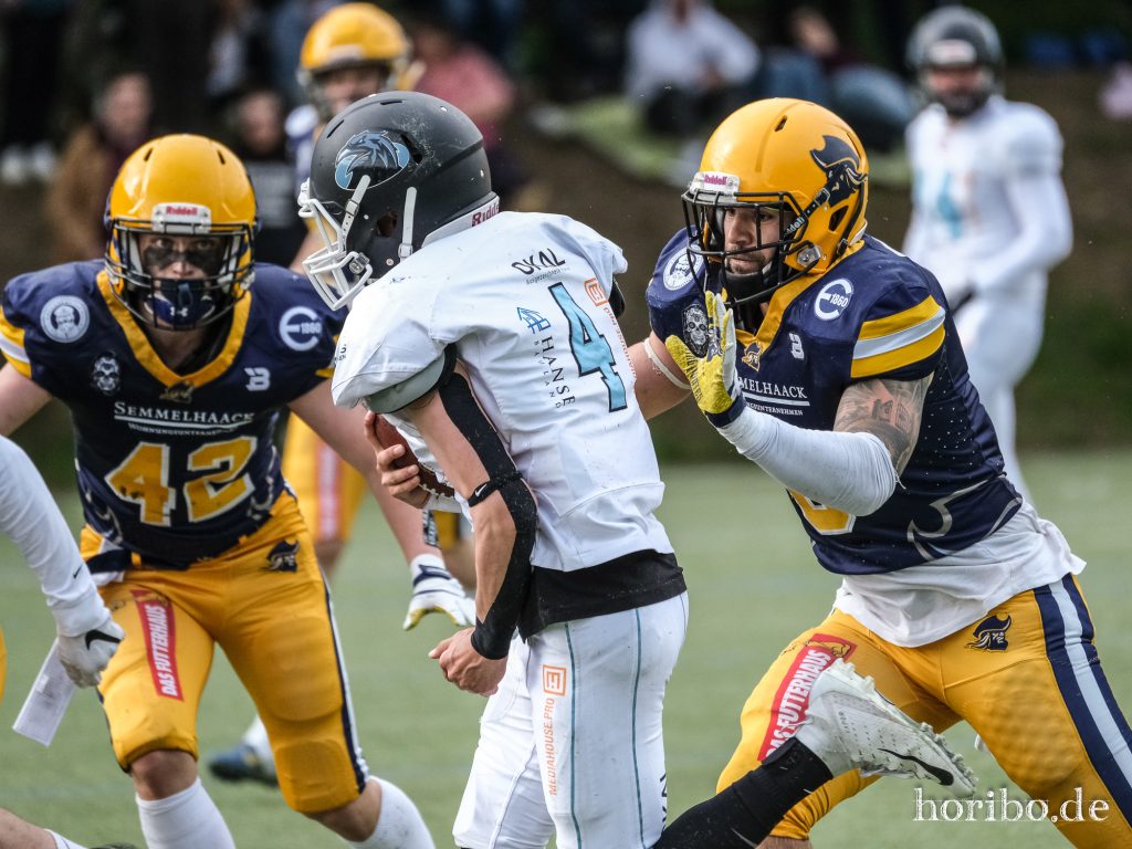 der balltragende Footballspieler wird von zwei Verteidigern angegriffen